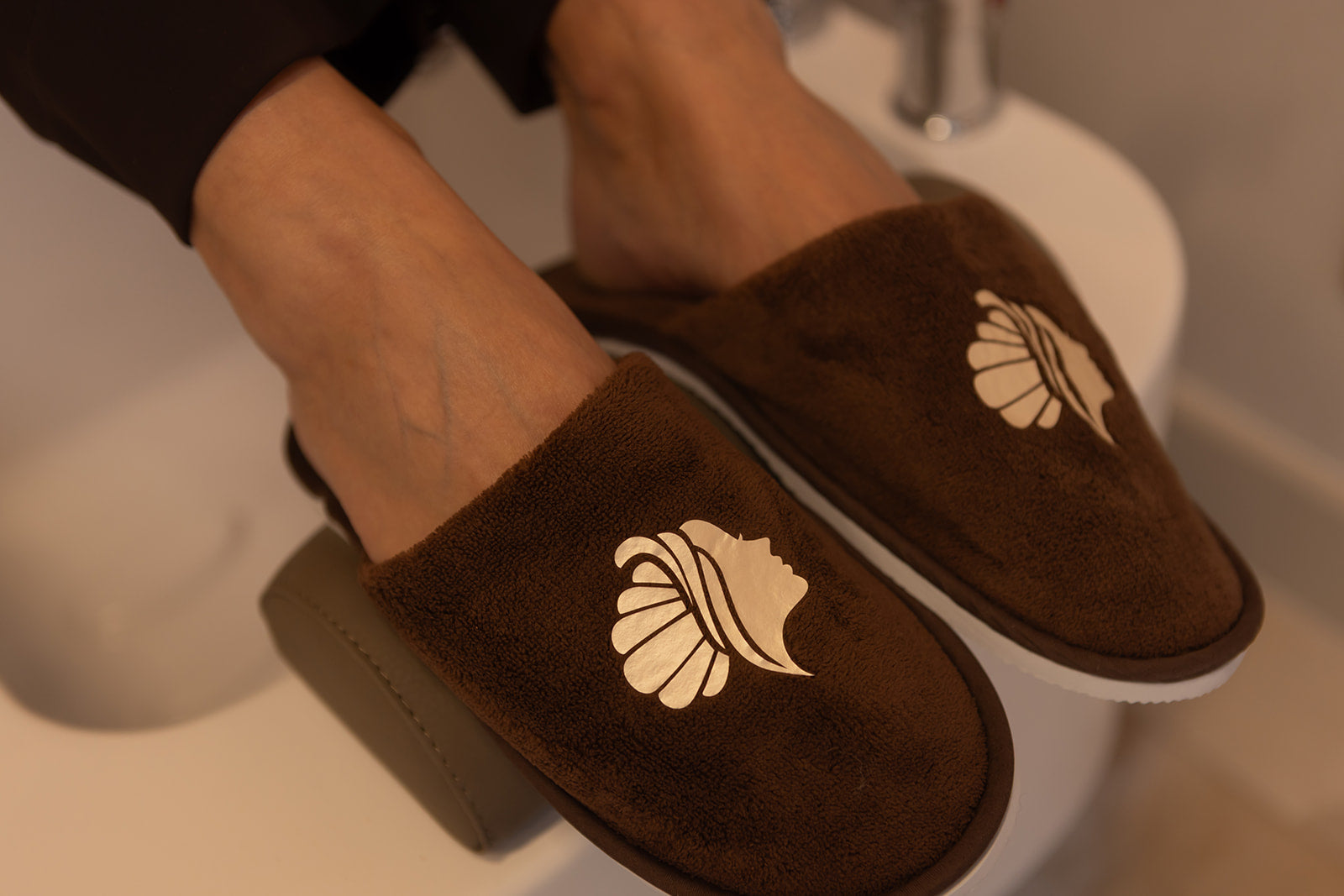 Detail van zachte bruine pantoffels met NSea Beauty logo. Persoonlijke aandacht vanaf het eerste moment.